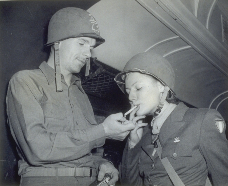 C1:002    Prvt. Nickolas M. Weber, AC, 39706311, Chicago, Illinois, shown at Camp Patrick Henry Railhead holding match while Pvt. Claudie M. Cleja, member of French Women's Army Corps (Shipment IJ-204-YI), lights her cigarette. Octiober 13, 1944 (LVA sc_21_img16)